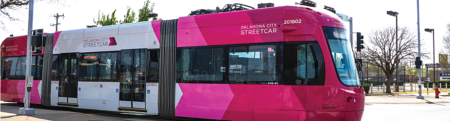 Redbud OKC Streetcar driving past corner with stoplights.