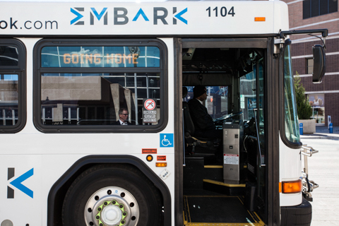 EMBARK transit professional driving a fixed-route bus in front of the Cox Convention Center.